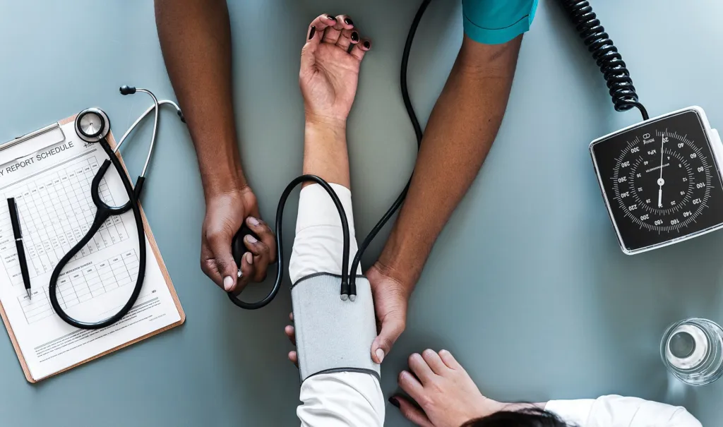 Healthcare worker measuring a patient's blood pressure with a cuff and stethoscope