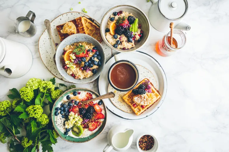 Overhead view of breakfast bowls with oats, berries and fruit on a marble table