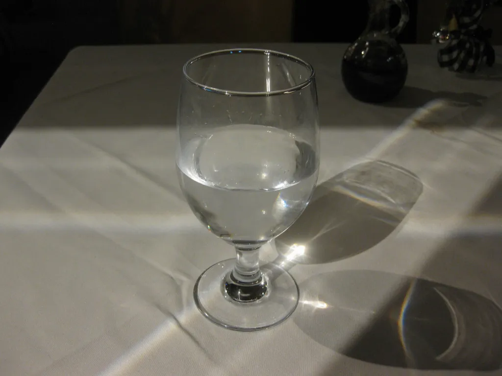 Clear glass of water on a white tablecloth in natural light