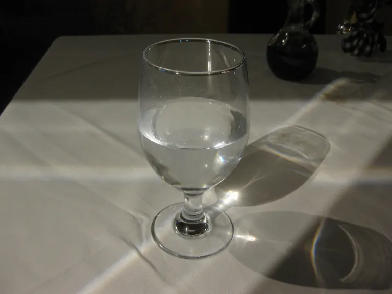 Clear glass of water on a white tablecloth in natural light