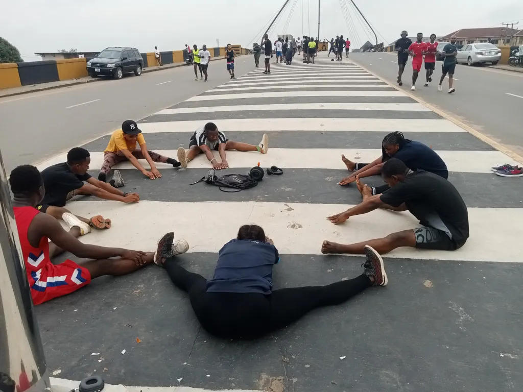 Group of people doing seated hamstring stretches outdoors before a workout