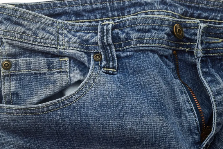 Close-up of blue denim jeans showing pocket, stitching and button