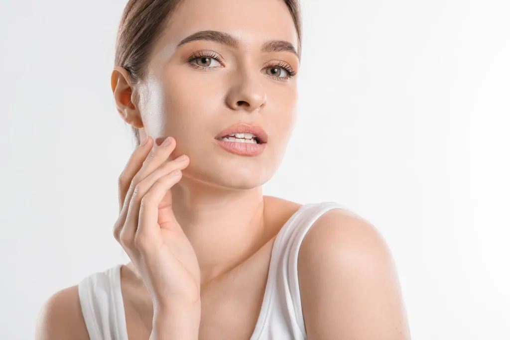 Woman gently touching her cheek with natural, healthy-looking skin