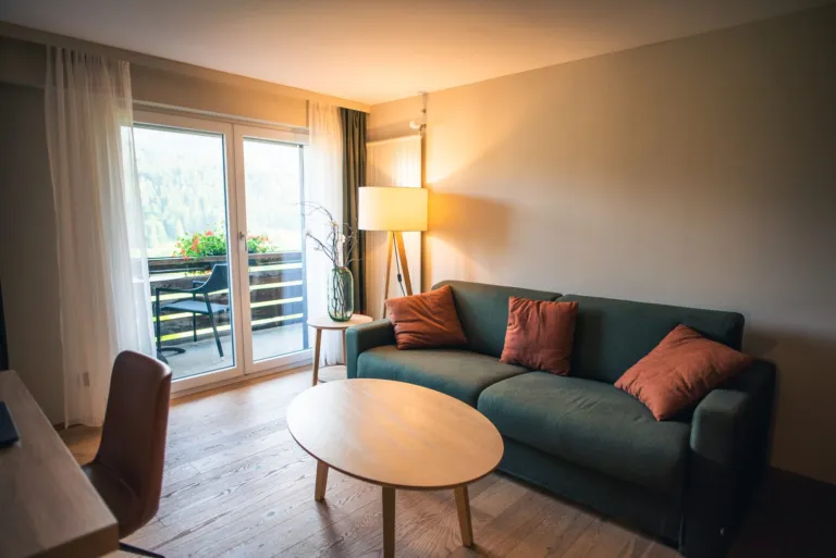Cozy living room with a green sofa, orange cushions and warm lamp light