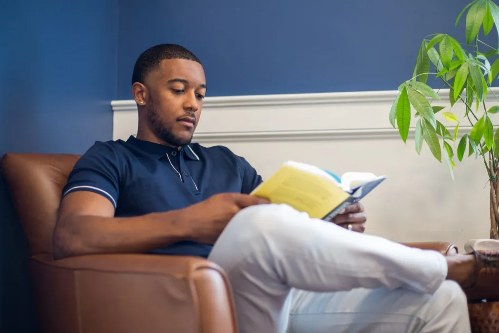 Man relaxing in a leather armchair while reading a book