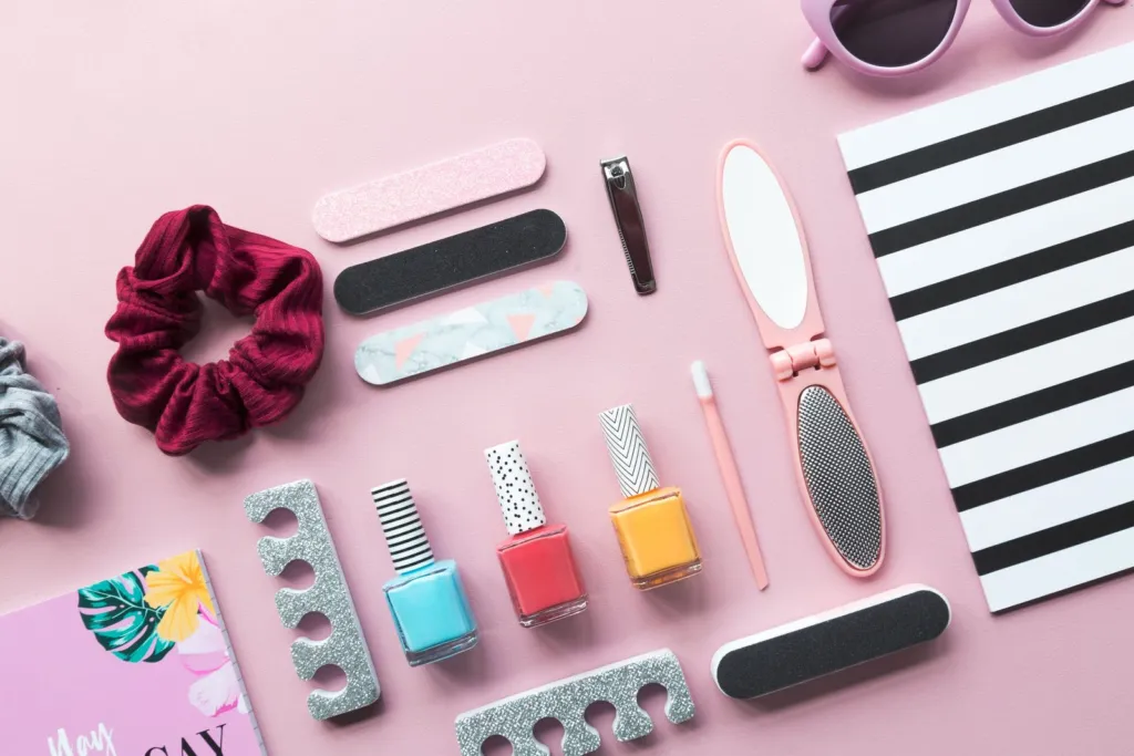 Nail polish bottles, nail files and manicure tools on a pink background