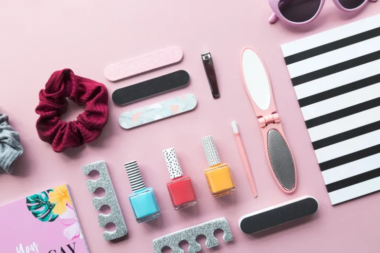 Nail polish bottles, nail files and manicure tools on a pink background