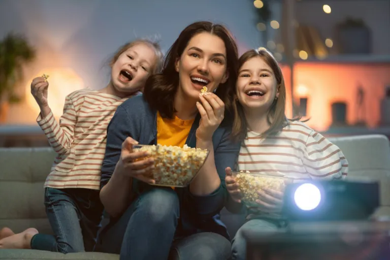 Family eating popcorn while watching a movie at home
