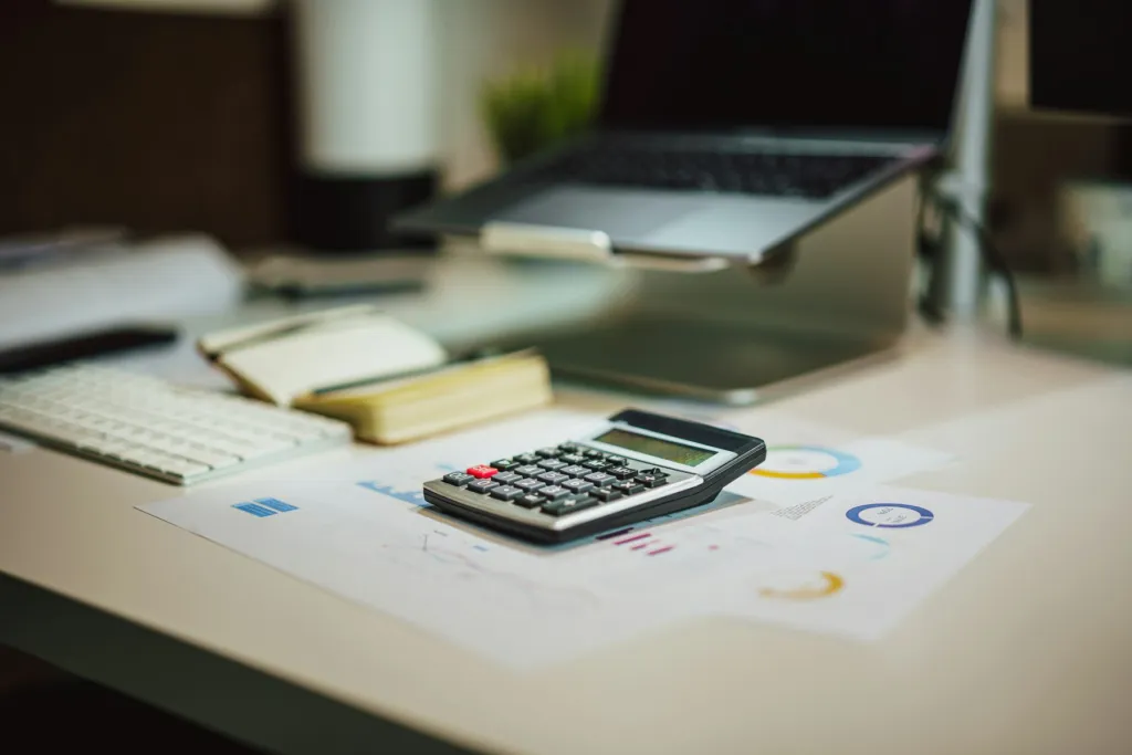 Organized study desk with a calculator, notebook and laptop for planning math tutoring costs