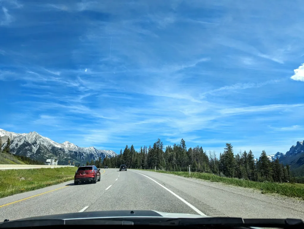 Car driving along a road with mountains in the background