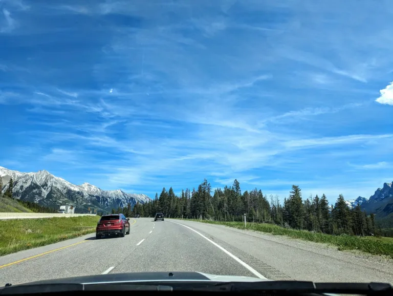 Car driving along a road with mountains in the background