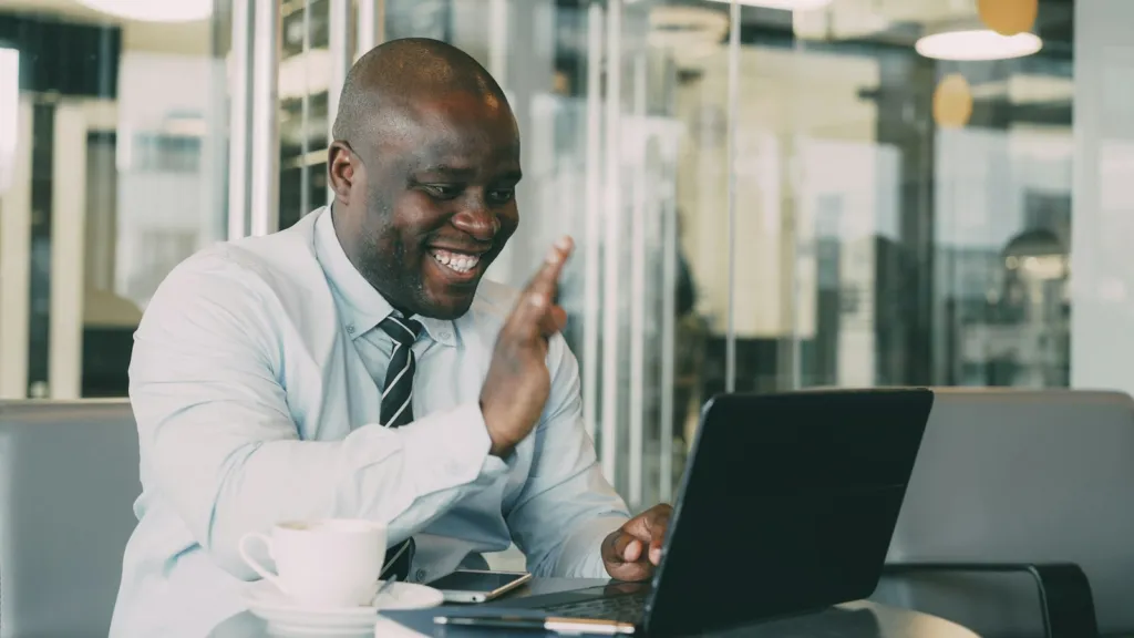 Man waving to a friend during a video call on a laptop
