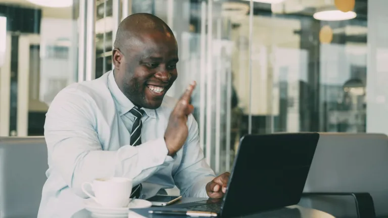 Man waving to a friend during a video call on a laptop