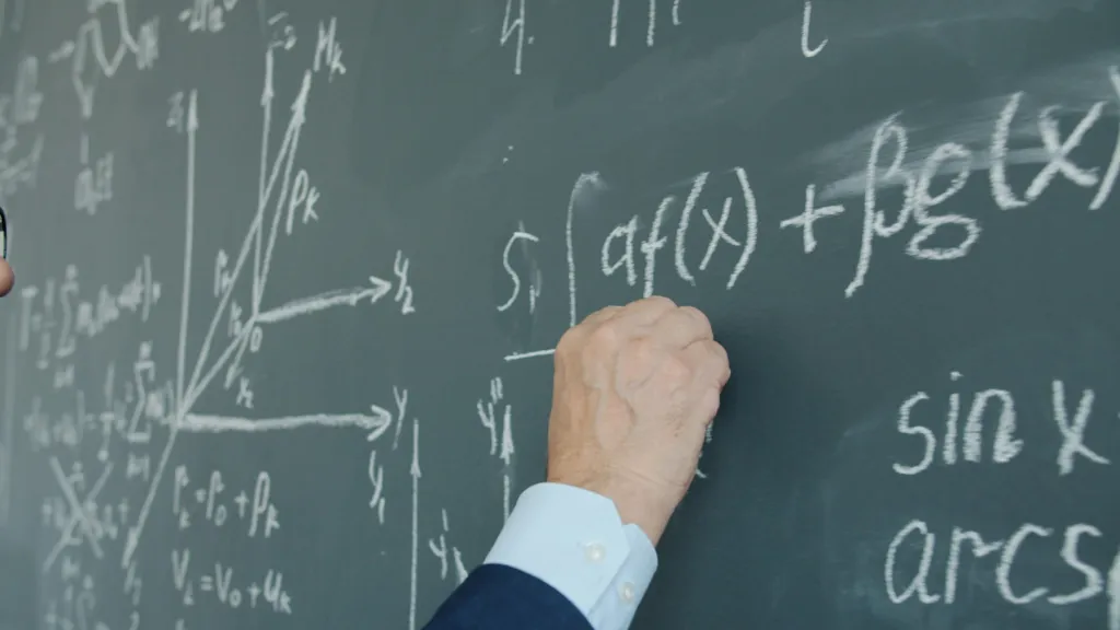 Math tutor explaining formulas and graphs on a chalkboard during a lesson