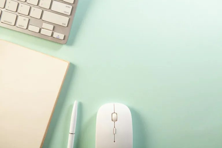 Tidy desk with a keyboard, notebook, pen and mouse