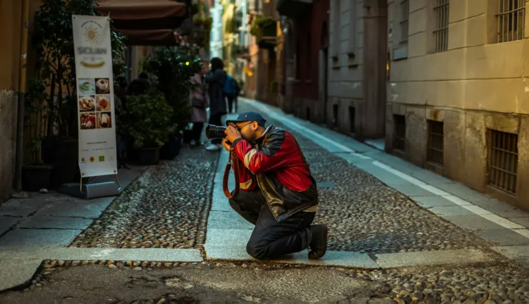 Photographer kneeling on a cobblestone street taking a photo