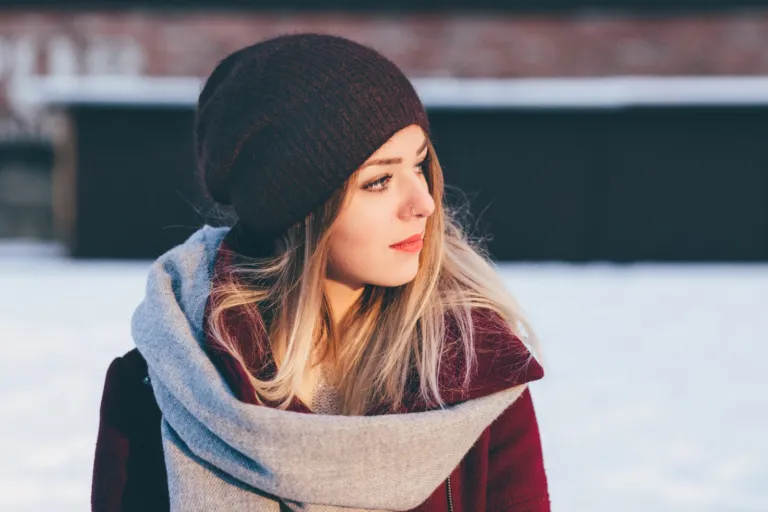 Woman in a knit hat and warm scarf outdoors in the snow